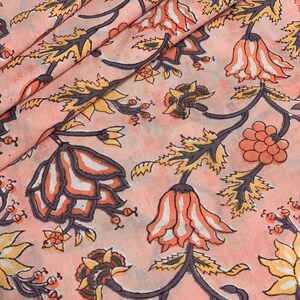 May include: Pink fabric with a floral print featuring a repeating pattern of orange, yellow, and white flowers with gray stems and leaves.