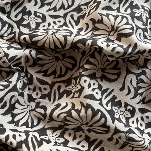 May include: Black and white fabric with a floral pattern. The fabric is wrinkled and has a soft, textured feel.