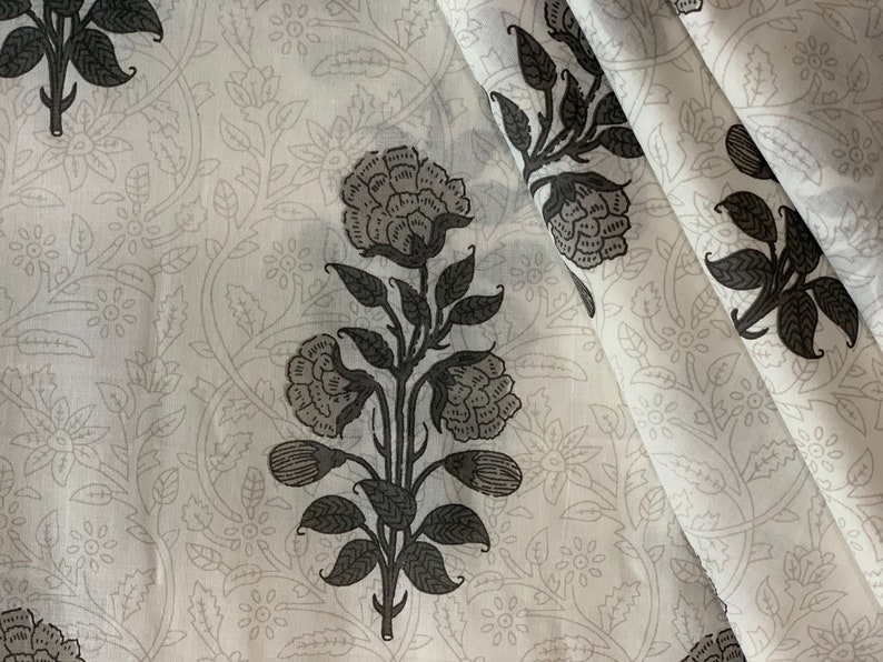 May include: White fabric with a black floral pattern. The fabric features a repeating design of stylized flowers and leaves.