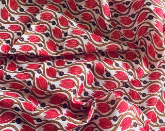 May include: White fabric with a repeating pattern of red tulips and brown stems. The fabric is folded and has a wavy texture.