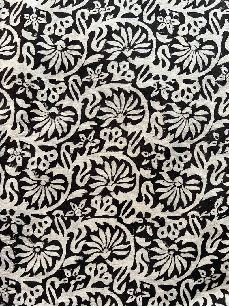 May include: Black and white fabric with a repeating floral pattern. The design features stylized flowers and leaves.