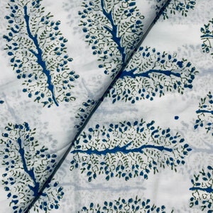 May include: White fabric with a repeating pattern of blue and green stylized tree branches. The fabric is folded in half, showing the pattern on both sides.