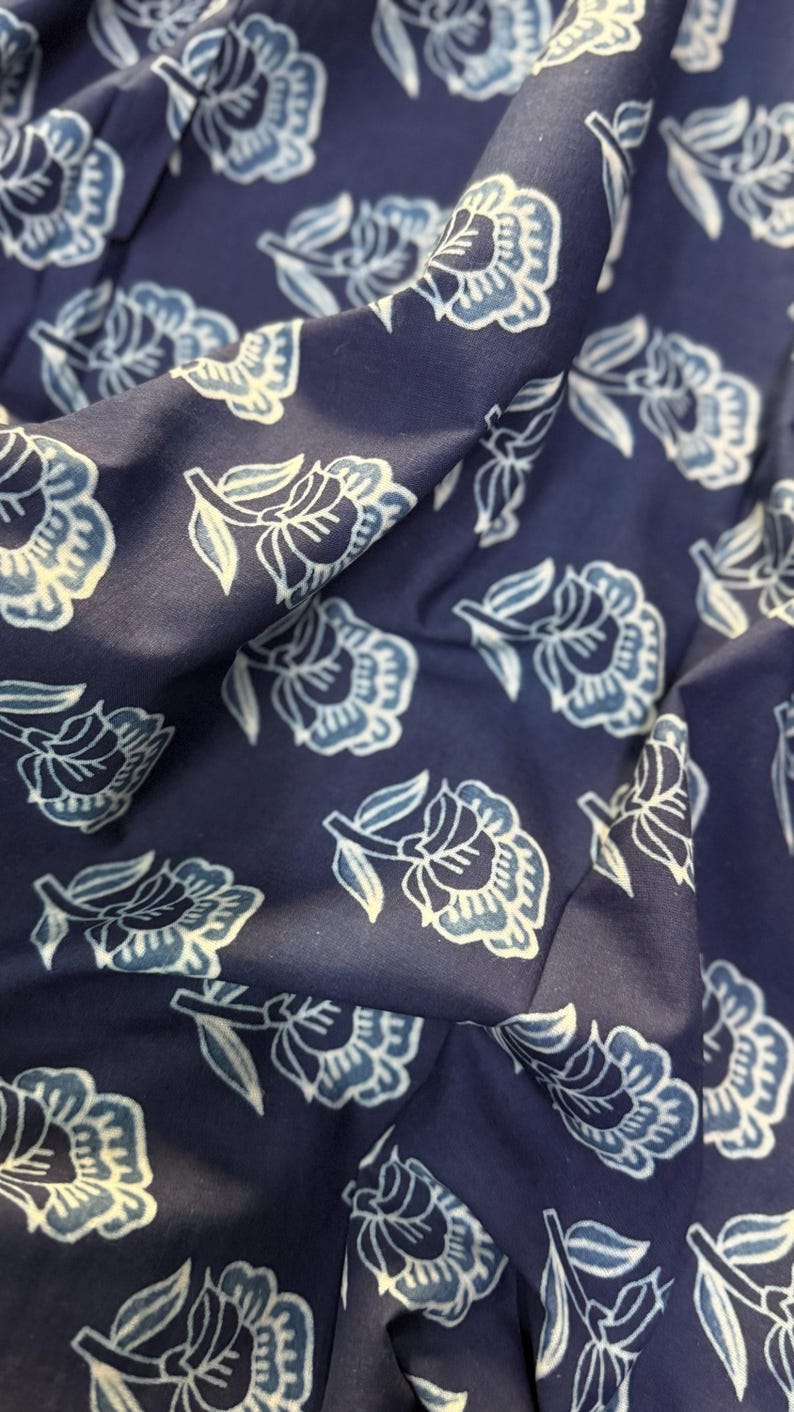 May include: A navy blue fabric with a white floral pattern. The fabric has a soft, textured feel and is perfect for crafting projects.