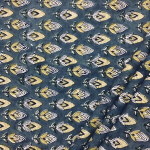 May include: A blue fabric with a repeating pattern of yellow and white stylized flowers. The flowers have a geometric design and are arranged in rows.