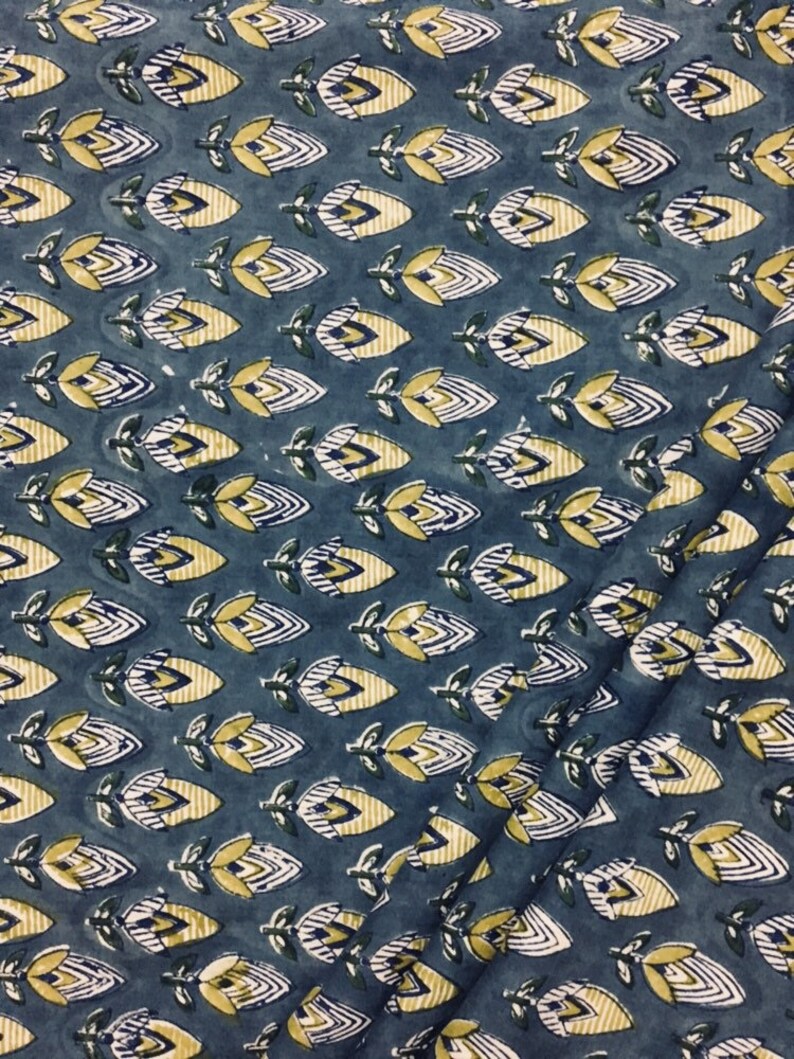 May include: A blue fabric with a repeating pattern of yellow and white stylized flowers. The flowers have a geometric design and are arranged in rows.