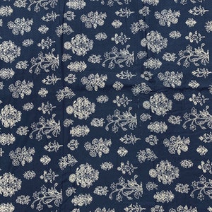 May include: A navy blue fabric with a white floral pattern. The fabric is covered in a repeating pattern of small white flowers and leaves.