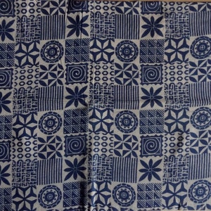 May include: A white fabric with a repeating pattern of blue geometric shapes and flowers. The pattern includes circles, squares, triangles, and stars.