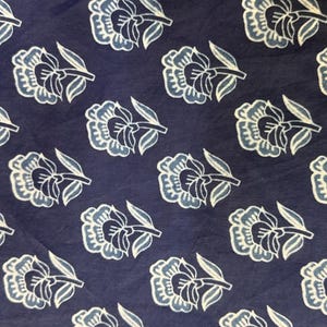 May include: A navy blue fabric with a white floral pattern. The flowers are stylized and have a slightly faded look.
