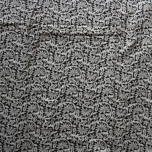 May include: Black and white fabric with a repeating floral pattern. The fabric has a subtle sheen and a soft texture.