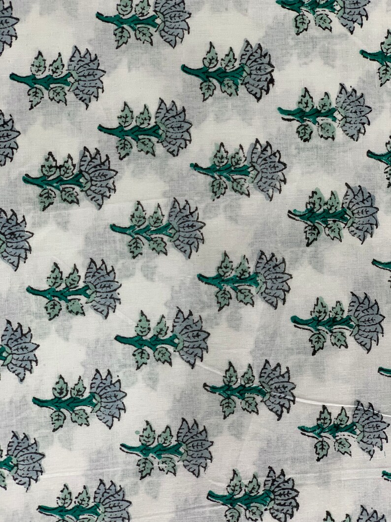 May include: White fabric with a repeating pattern of blue and green floral designs. The flowers are stylised and have a traditional Indian look.