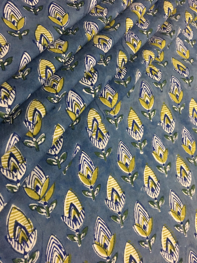 May include: Blue fabric with a repeating pattern of yellow, white, and blue stylized flowers. The fabric has a slightly textured surface.