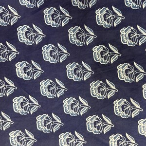 May include: A navy blue fabric with a white and light blue floral pattern. The fabric has a repeating pattern of stylized flowers with a single stem.