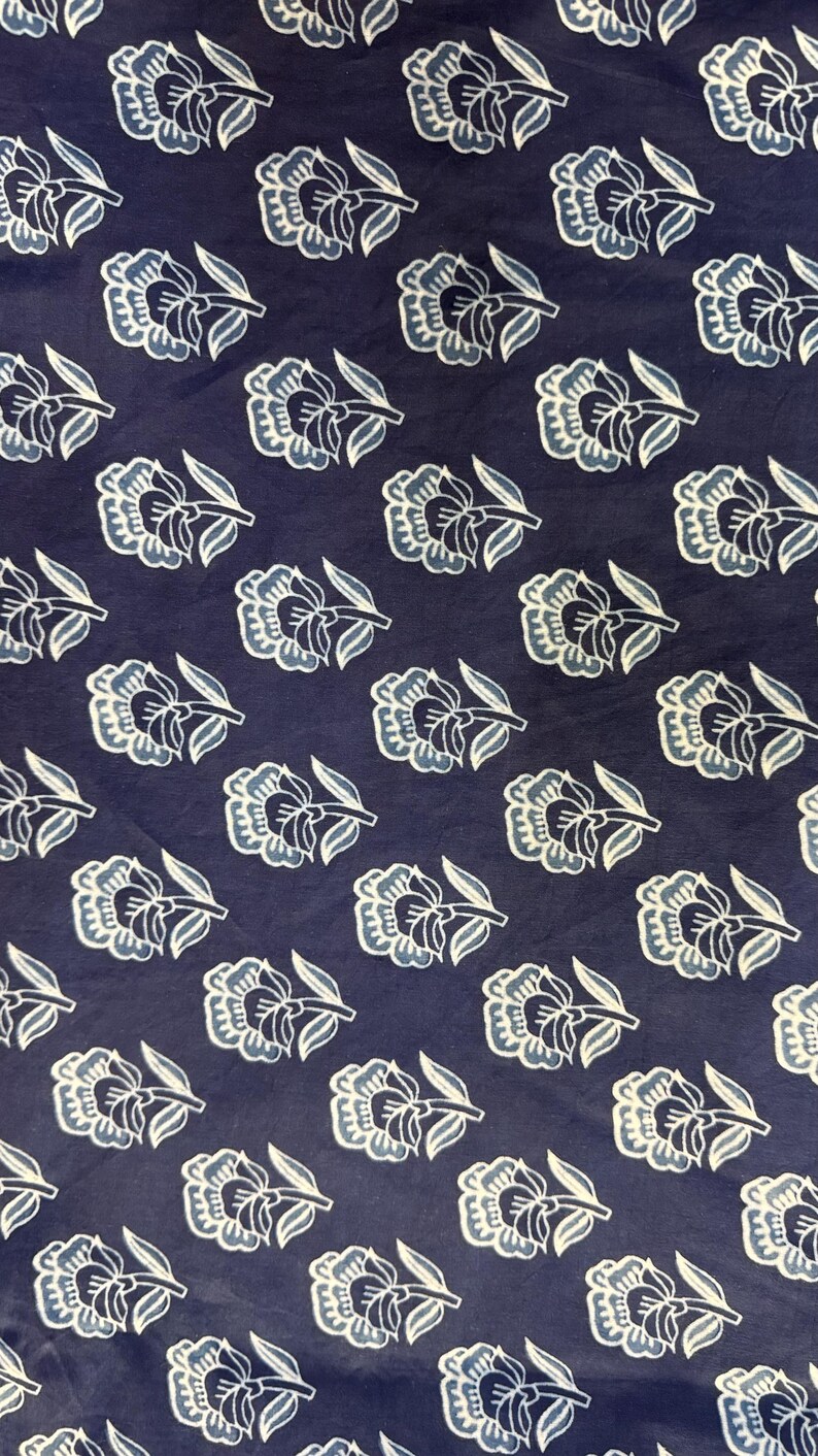 May include: A navy blue fabric with a white and light blue floral pattern. The fabric has a repeating pattern of stylized flowers with a single stem.