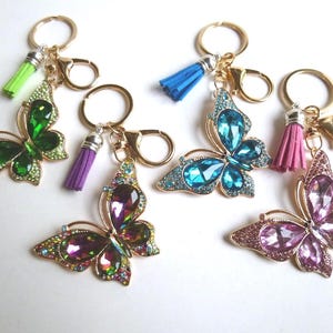 May include: A collection of butterfly keychains with gold-tone metal frames and colorful rhinestone accents. Each keychain features a different color butterfly, including green, blue, purple, and pink, with matching tassel details.