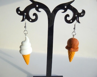 May include: A pair of ice cream cone earrings. One earring features a white soft serve ice cream cone and the other earring features a brown chocolate ice cream cone.