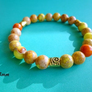 May include: A yellow and orange gemstone bracelet with a gold accent bead. The beads are 8 mm in diameter.