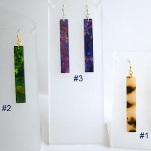 May include: Three pairs of dangle earrings with different patterns. The earrings are displayed on a white background. The earrings are labeled #1, #2, and #3.
