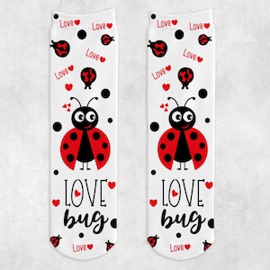 May include: A pair of white socks with a red ladybug design and the text "LOVE bug." The socks have a black polka dot pattern and red hearts.