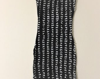 May include: A black sleeveless dress with a white bow pattern. The dress is fitted and has a scoop neck.