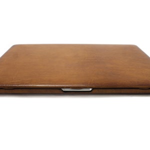 May include: A brown leather laptop case with a smooth, textured surface.