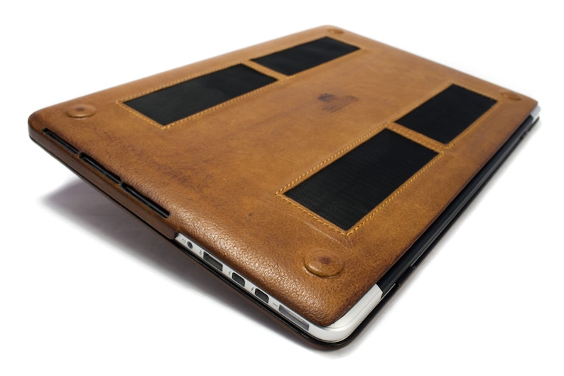 May include: A brown leather laptop case with black mesh panels for ventilation. The case has a silver zipper and a silver trim around the edges.
