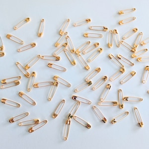 100 imperdibles de color dorado muy pequeños. Imperdibles de aleación de metal de 3/4 de pulgada de largo.