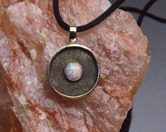 A Fire Filled 8mm Round Simulated Opal Set On Round Sterling Silver. A Raised Border and Blackened Background  Makes the Fire Stand Out.