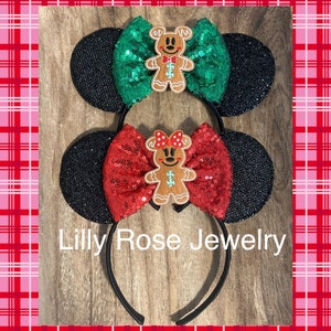 Op de afbeelding: Twee zwarte, met pailletten bezette muisoren-haarbanden met een peperkoekmannetje en een met pailletten bezette strik. De ene strik is groen, de andere is rood. De tekst "Lilly Rose Jewelry" staat op de haarband.