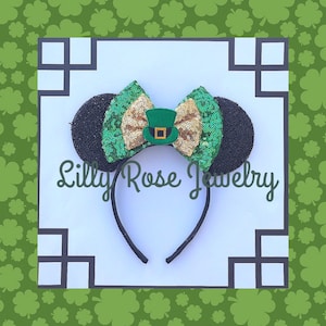 May include: Black and green sequin Minnie Mouse ears headband with a gold bow and a green leprechaun hat. The headband says "Lilly Rose Jewelry".
