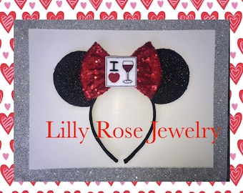 May include: Red and black mouse ears headband with a red sequin bow and a white card with the text "I love wine" and a red heart and a wine glass graphic.