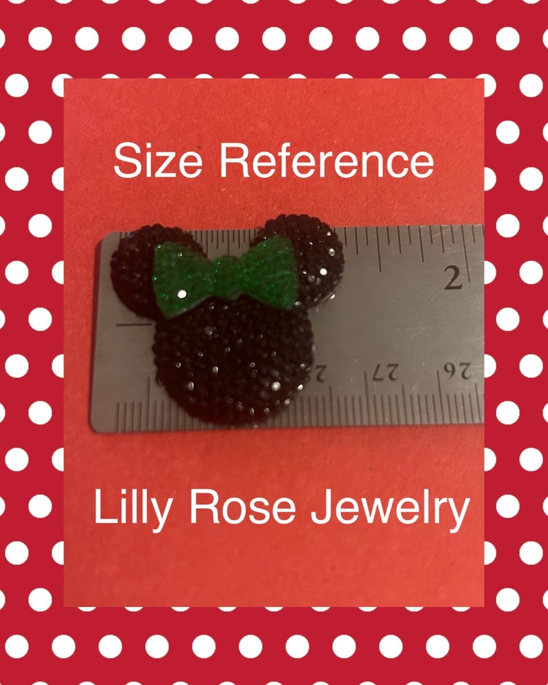 May include: Black and green rhinestone Mickey Mouse head with a bow, measuring approximately 2 inches in diameter. Size reference image for Lilly Rose Jewelry.