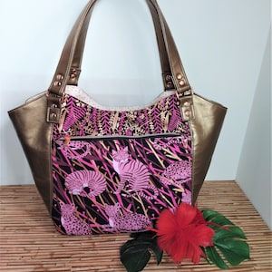 May include: A large, brown leather tote bag with a pink and black fabric lining featuring a repeating pattern of pink leopards on a black background. The bag has a zippered pocket on the front and two top handles.