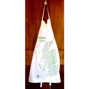 Peut inclure: Tablier blanc avec un contour vert de l'Écosse et le texte "Scottish Gin" imprimé dessus.