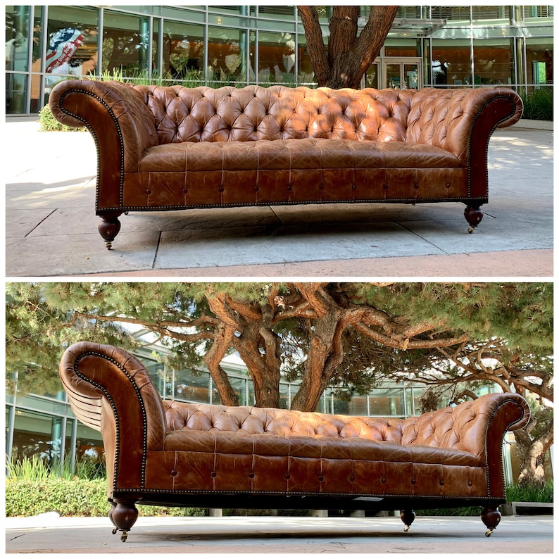 May include: A brown leather Chesterfield sofa with button tufting and wooden legs. The sofa is positioned outdoors on a paved surface.