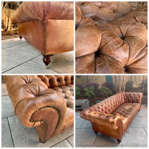 May include: A brown leather sofa with tufted buttons and wooden legs. The sofa is in a living room setting with plants and a patio in the background.