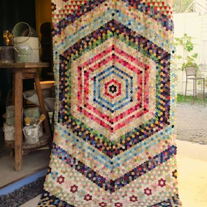 May include: A large, colourful quilt made of patchwork fabric. The quilt is made up of many hexagonal shapes, each with a different pattern. The quilt is a beautiful example of traditional quilting.