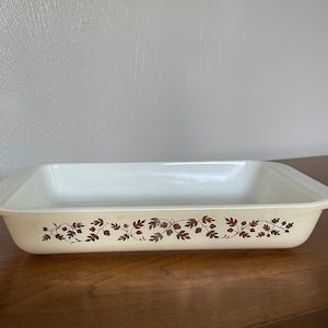 May include: A white rectangular baking dish with brown floral design. The dish has two handles on the sides.