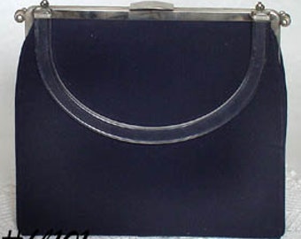 May include: A dark navy blue handbag featuring a smooth fabric exterior, a silver-toned metal frame, a top clasp closure, and a semi-circular handle integrated into the front panel. The text #hb101 is visible in the bottom left corner.