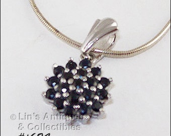 May include: A silver pendant necklace with a cluster of small, dark blue gemstones set in a flower shape.