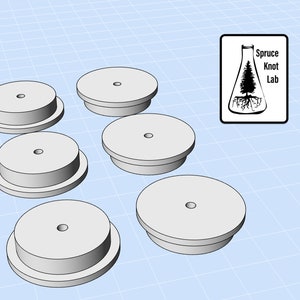 Puede incluir: Seis bases redondas de madera blanca con un pequeño agujero en el centro. Las bases están apiladas en dos capas.