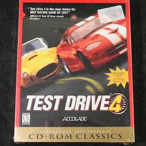 May include: A Test Drive 4 CD-ROM Classics video game box featuring a red sports car and a yellow sports car on the cover. The text reads Test Drive 4, Electronic Arts Presents, and includes an ESRB Everyone rating and E3 award information.