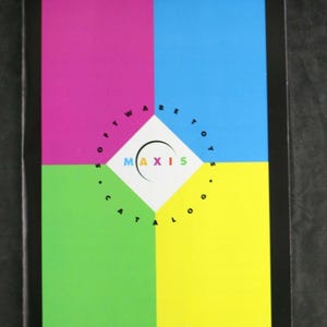 May include: A rectangular catalog with a black border featuring four large color blocks in magenta, cyan, lime green, and yellow. A white diamond in the center displays the text MAXIS with a curved black line and the words SOFTWARE TOYS CATALOG.