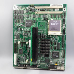 May include: A green printed circuit board featuring an Intel 486 SX processor, multiple black expansion slots, an ACC Micro chip, and various integrated circuits. The board includes white connector ports and a vertical black expansion card installed.