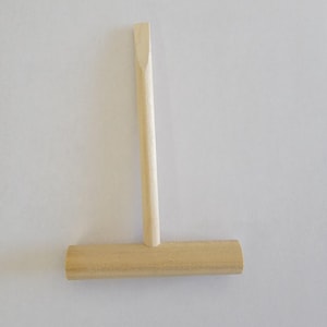 Puede incluir: Un rodillo de masa de madera con un mango largo. El rodillo es de color marrón claro y tiene una superficie lisa. El mango también es de color marrón claro y tiene una forma ligeramente redondeada.