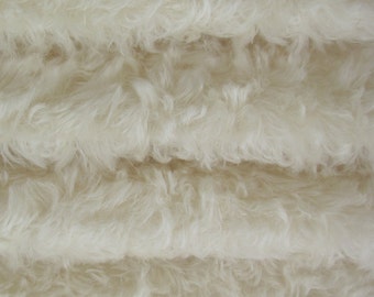 May include: Close-up of a white fluffy fabric with a soft, plush texture. The fabric is folded in layers, creating a sense of depth and dimension.