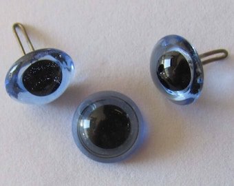 May include: Three blue glass eyes with black pupils and silver metal loops for attaching to a craft project.