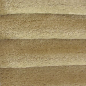 May include: Close-up of a soft, brown, plush fabric with a fuzzy texture. The fabric is folded into four layers, creating a layered effect.