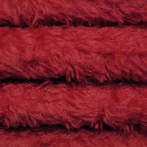Puede incluir: Primer plano de una tela de piel sintética de color rojo oscuro. La tela está doblada en cuatro capas, mostrando la textura y la suavidad del material.