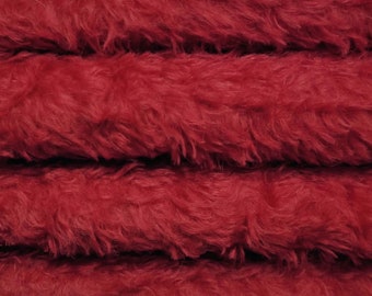 May include: Close-up of a deep red faux fur fabric. The fabric is folded into four layers, showing the texture and softness of the material.