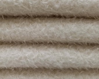 May include: Close-up of a stack of four white fluffy blankets. The blankets are soft and plush, with a fuzzy texture.